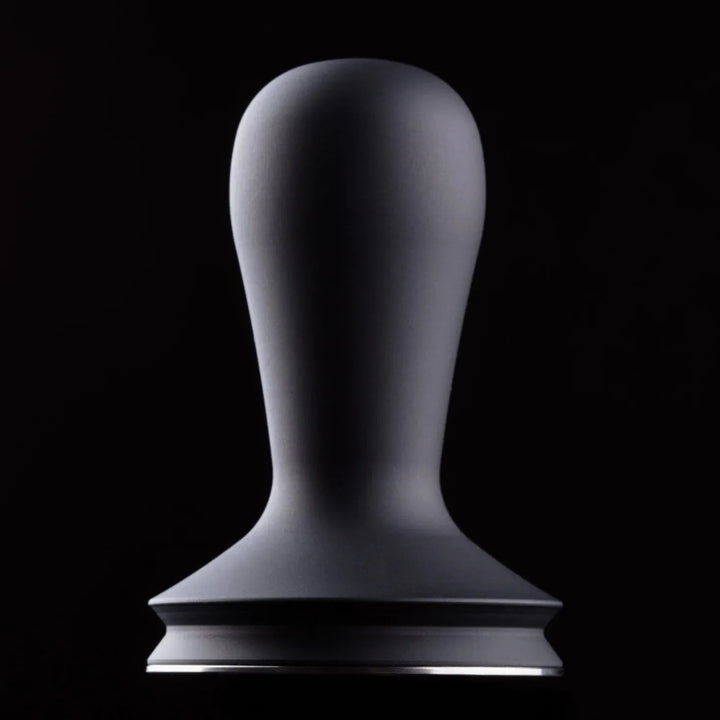 A matte black coffee tamp with a tapered handle and a wide flat base, centered against a solid black background.