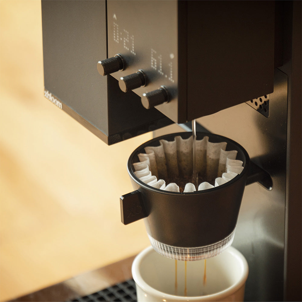 Midnight Black XBloom Studio Coffee Machine brewing a cup of coffee with a focus on the filter and stream.