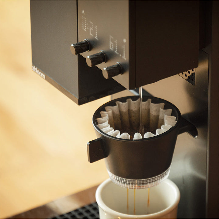 Midnight Black XBloom Studio Coffee Machine brewing a cup of coffee with a focus on the filter and stream.