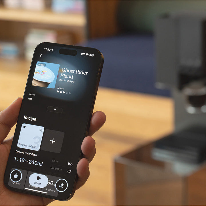 Hand holding a smartphone with a coffee app for the Midnight Black XBloom Studio Coffee Machine, displaying a coffee recipe.