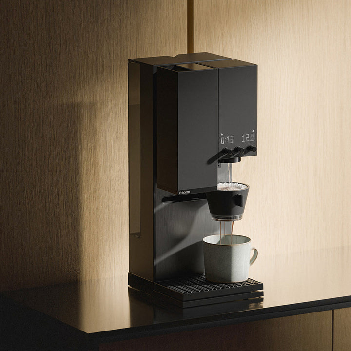 Midnight Black XBloom Studio Coffee Machine dispensing a cup of coffee on a wooden surface