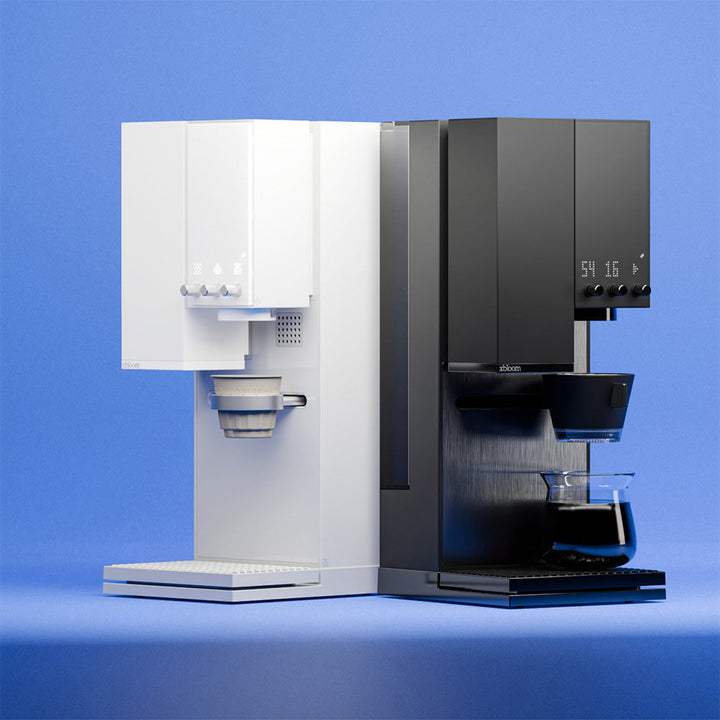 Two XBloom Studio Coffee Machines, one white and one black, on a blue background