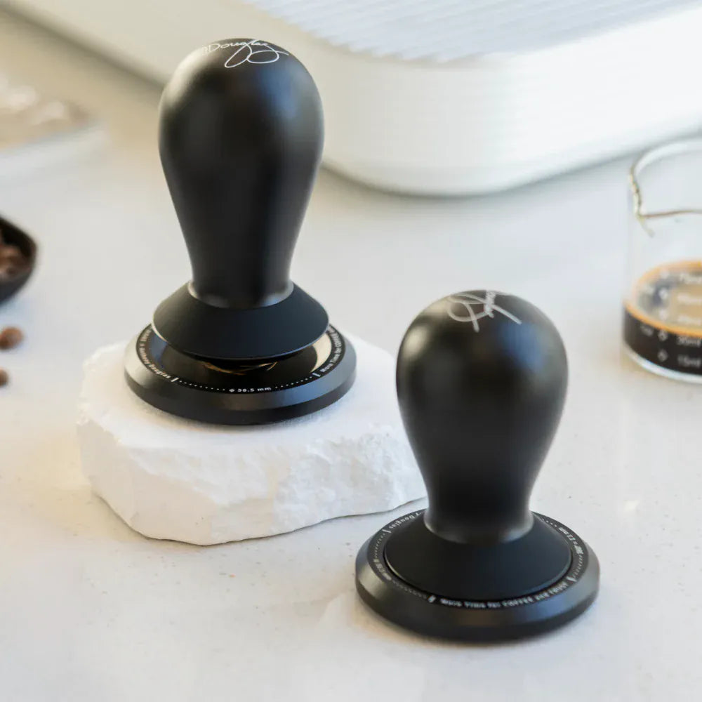 TIMEMORE FLOW Small and Large tampers displayed on a marble countertop beside a coffee measuring beaker