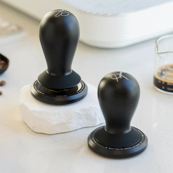 TIMEMORE FLOW Small and Large tampers displayed on a marble countertop beside a coffee measuring beaker