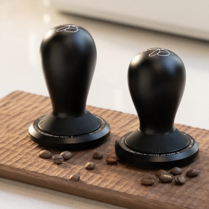 TIMEMORE FLOW tampers in Small and Large sizes displayed together on a wooden board with coffee beans