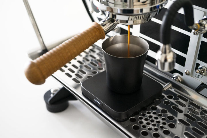 Acaia Umbra Lunar weighing a shot under an espresso machine group head