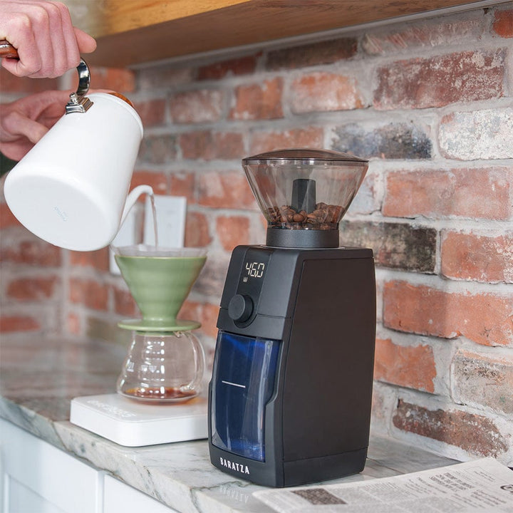 Baratza Encore ESP Pro Electric Coffee Grinder on a kitchen counter with a brick wall background