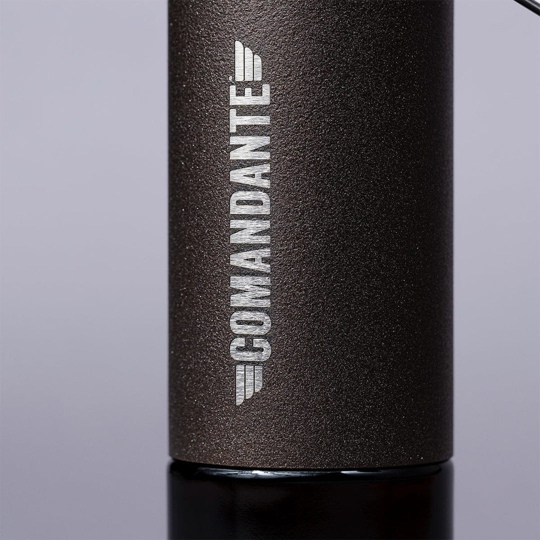 Close-up of Comandante C40 Nitro Blade Coffee Grinder MK4 in Copper Mountain with 'Comandante' branding on a grey background.