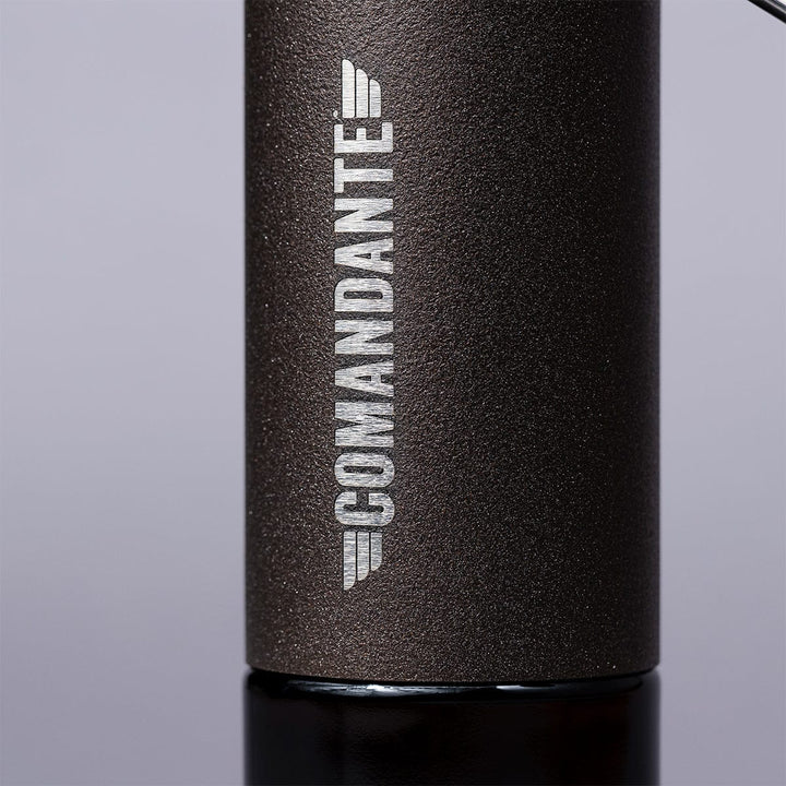 Close-up of Comandante C40 Nitro Blade Coffee Grinder MK4 in Copper Mountain with 'Comandante' branding on a grey background.