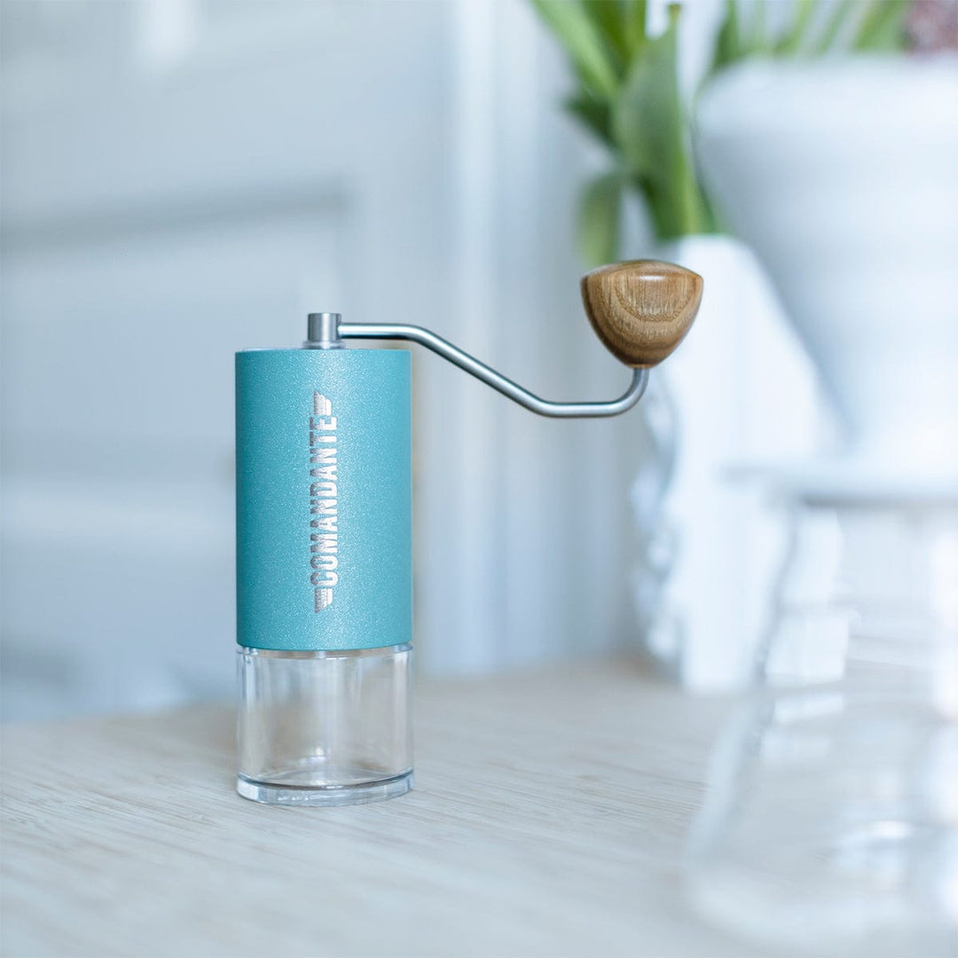 Comandante C40 Nitro Blade Coffee Grinder MK4 in Alpine Lagoon on a light surface with a blurred background