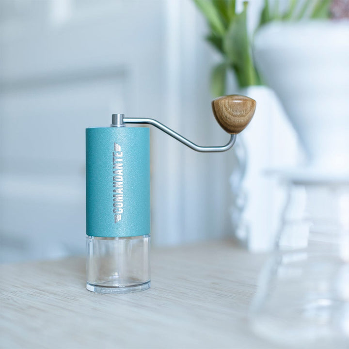 Comandante C40 Nitro Blade Coffee Grinder MK4 in Alpine Lagoon on a light surface with a blurred background