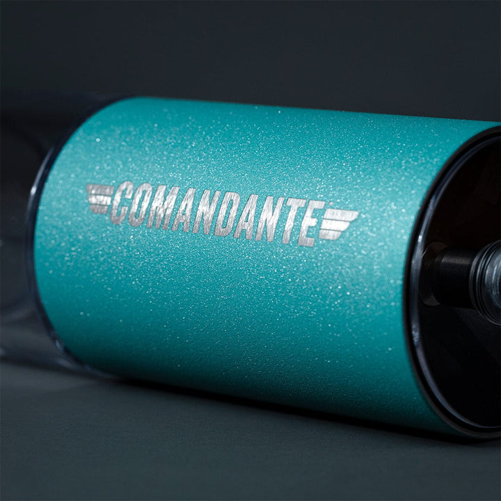Close-up of a Comandante C40 Nitro Blade Coffee Grinder MK4 in Alpine Lagoon with 'Comandante' branding on a dark background