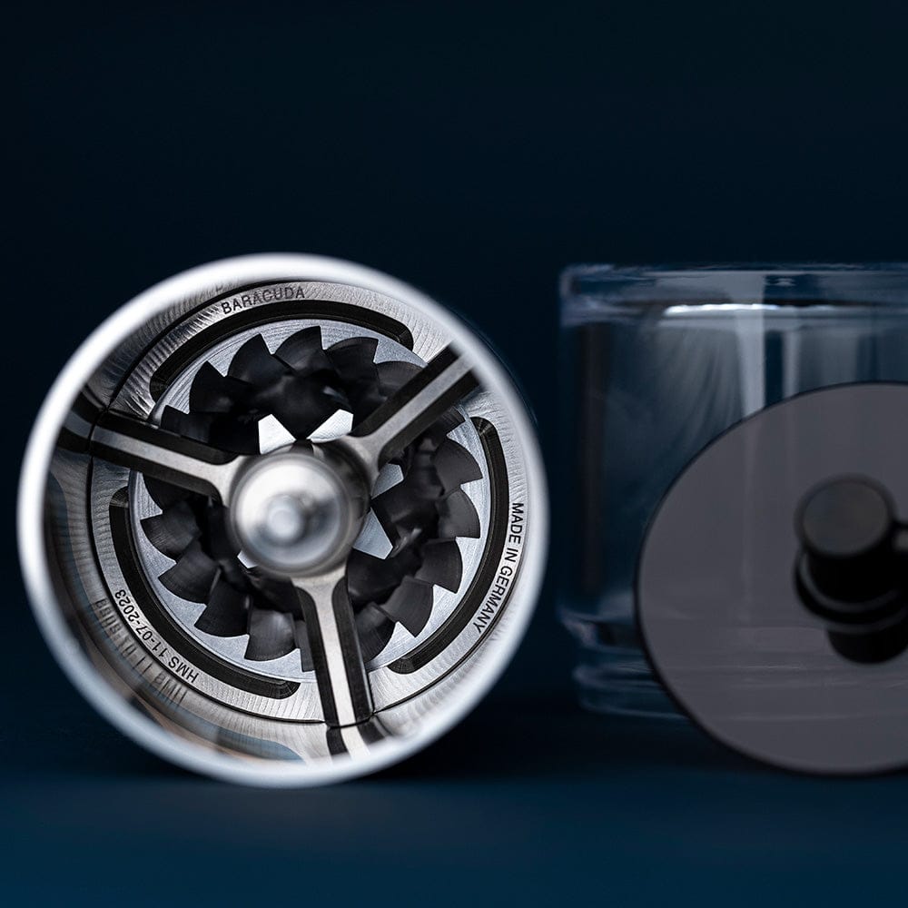 Close-up of the top view of the Comandante C60 Baracuda Coffee Grinder in Velvet Steel with 'Baracuda' branding on a dark background