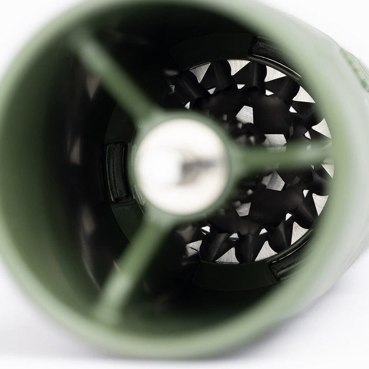 Close-up of a Comandante X25 Trailmaster Coffee Grinder in Forest Green with a stainless steel interior on a white background