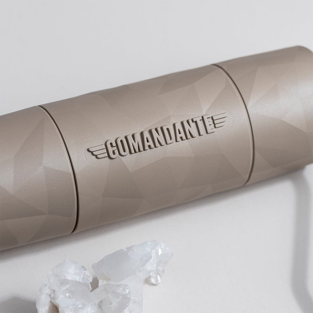 Close-up of Comandante X25 Trailmaster Dune Coffee Grinder with 'Comandante' branding on a white surface