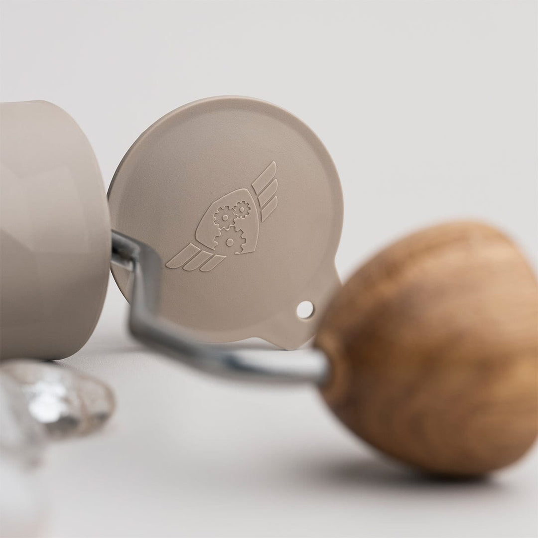 Close-up of a Comandante X25 Trailmaster Dune Coffee Grinder components on a light background