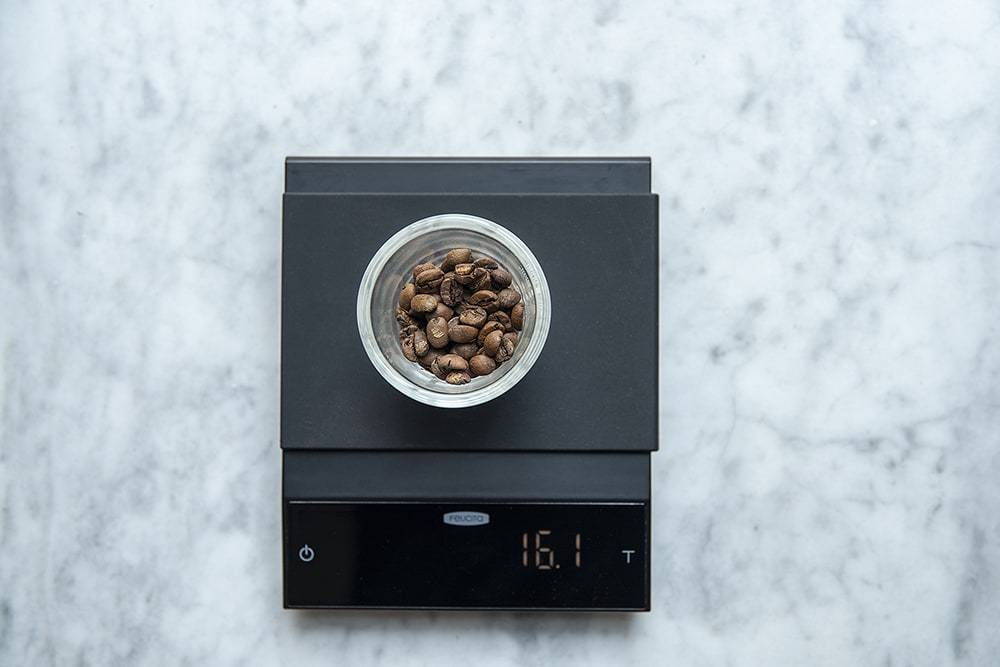 Felicita Incline Coffee Scale with a bowl of coffee beans on a marble surface
