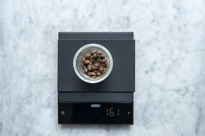 Felicita Incline Coffee Scale with a bowl of coffee beans on a marble surface