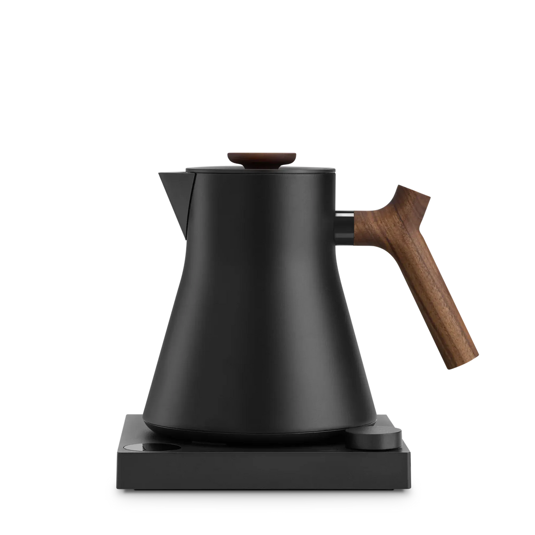 The Fellow Corvo EKG Pro Electric Kettle in Matte Black with a Walnut wooden handle on a white background