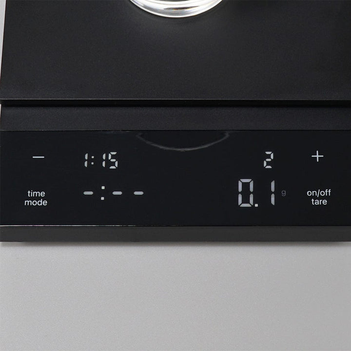 Hario Polaris Coffee Scale in Black with time, mode, weight, and tare display on a grey background