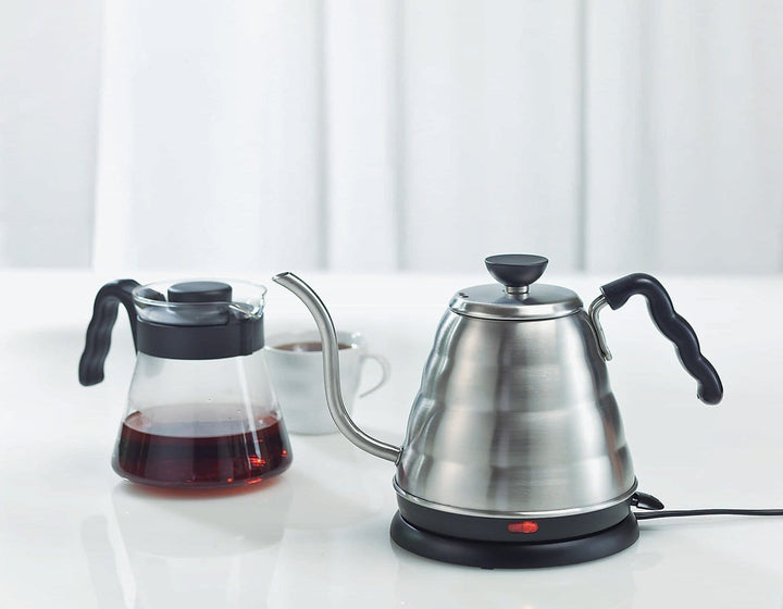 Hario V60 Buono Electric Drip Kettle with 800ml Capacity and glass carafe with liquid on a white surface