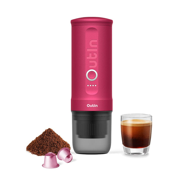 OutIn Nano Portable Espresso Coffee Machine in Fuchsia Pink with a glass of coffee and coffee grounds on a white background
