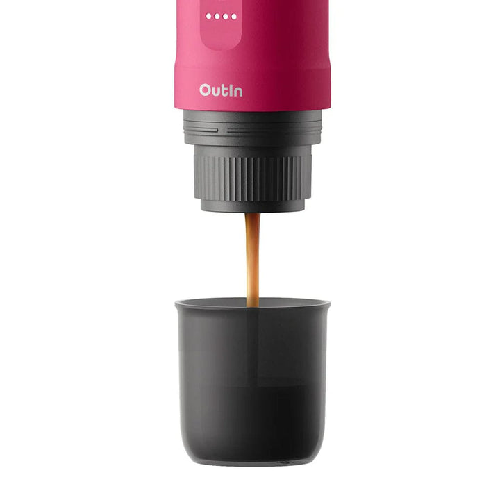 OutIn Nano Portable Espresso Coffee Machine in Fuchsia Pink with coffee being dispensed into a black cup on a white background