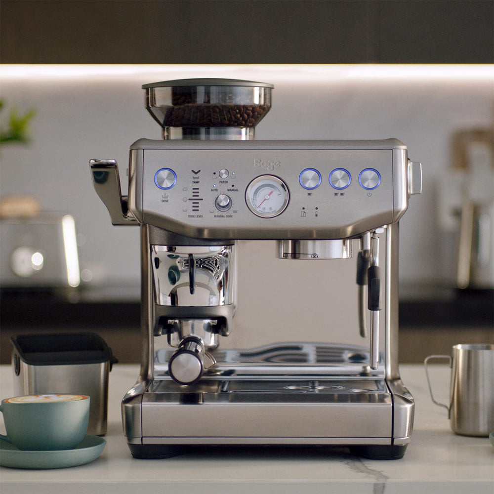 Stainless steel Sage Barista Express Impress Espresso Machine on a kitchen counter with blurred background