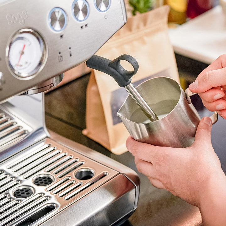 Person using a milk frother with a stainless steel Sage Barista Express Impress Espresso Machine