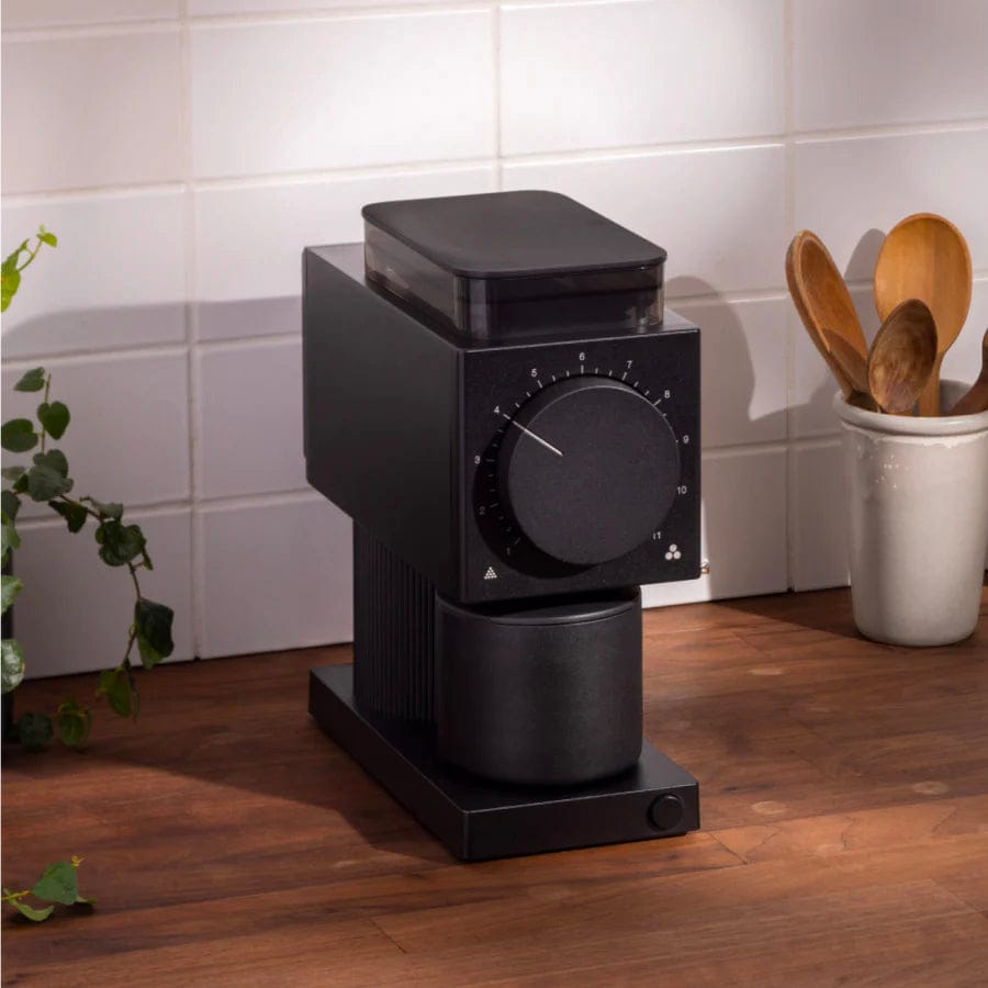Black Fellow Ode Gen 2 Electric Coffee Grinder on a wooden surface with a tiled wall background