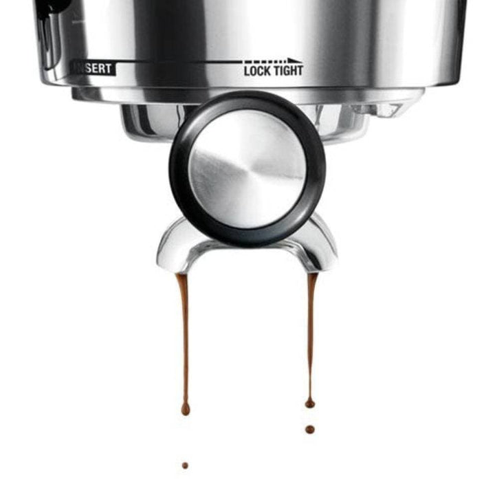 The Sage Dual Boiler Black Truffle Espresso Coffee Machine group head with coffee dripping onto a white background
